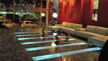 Een moderne lobby met een marmeren vloer, een witte bank en een glazen salontafel.
