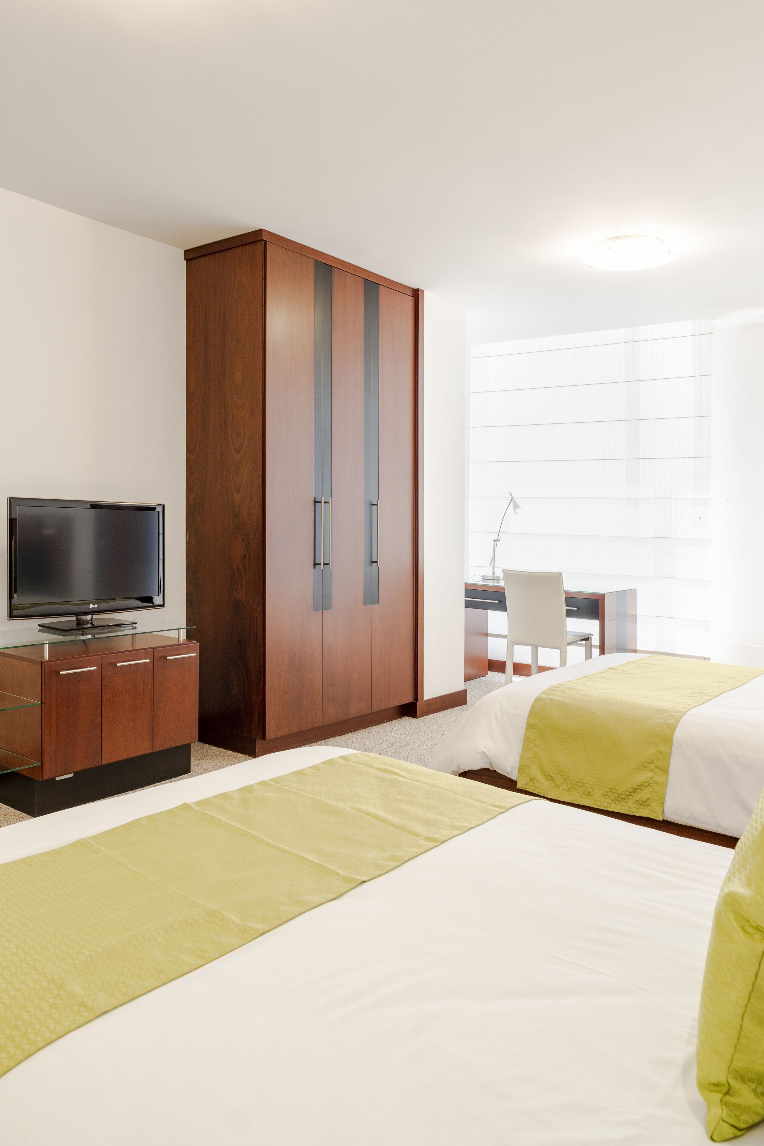 Une chambre d’hôtel avec deux lits, une télévision, un bureau et une armoire.