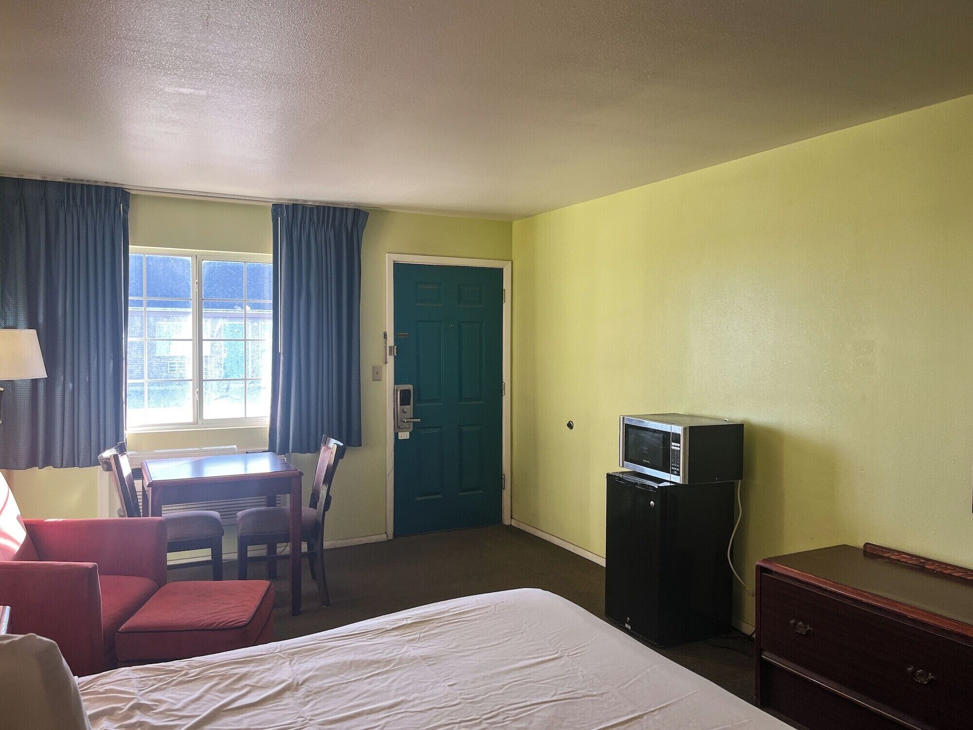 Ein Hotelzimmer mit Bett, Schreibtisch, Stuhl, Fernseher und Kommode.