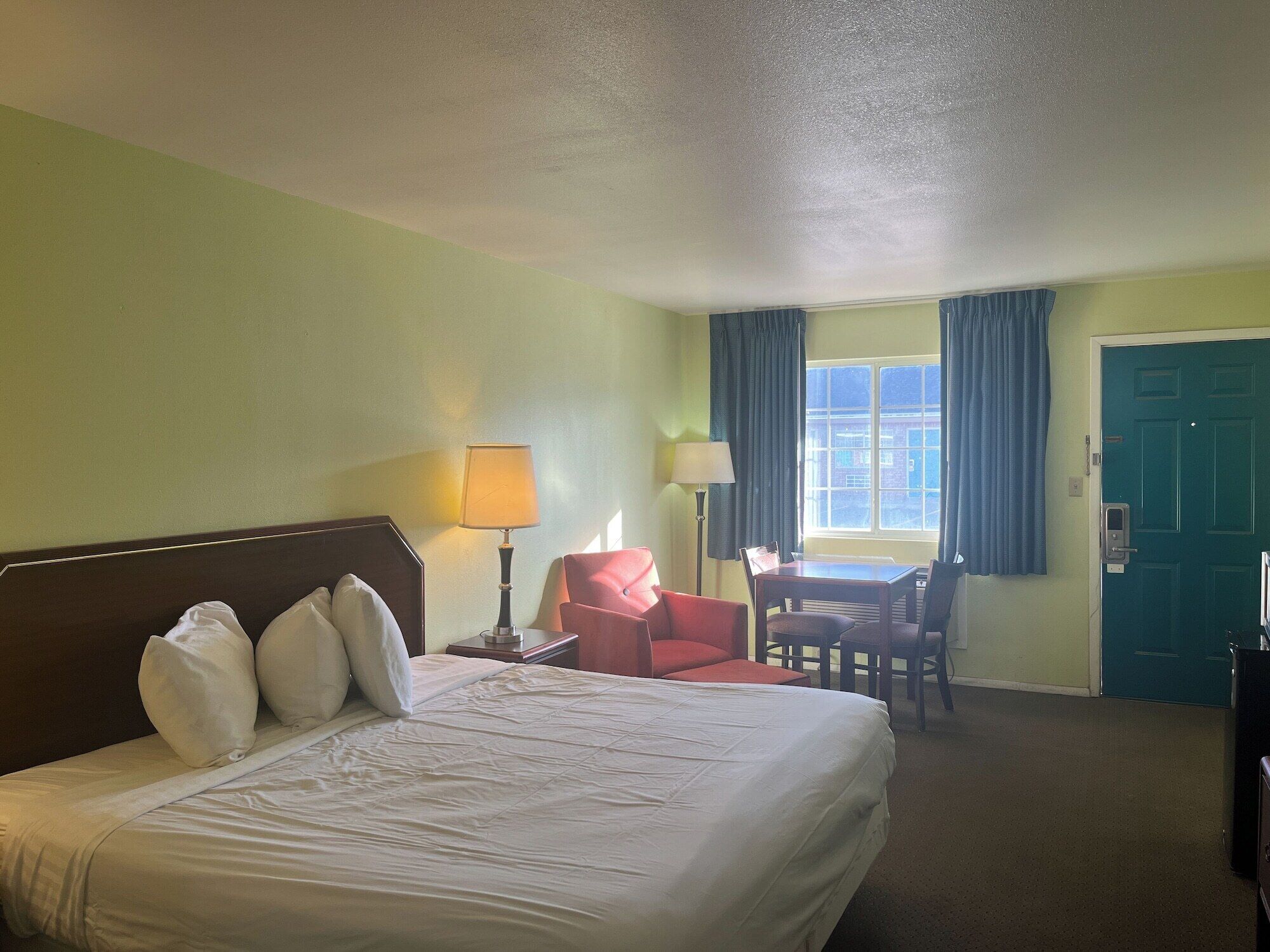 Een hotelkamer met een groot bed, een bureau, twee stoelen en een raam met gordijnen.