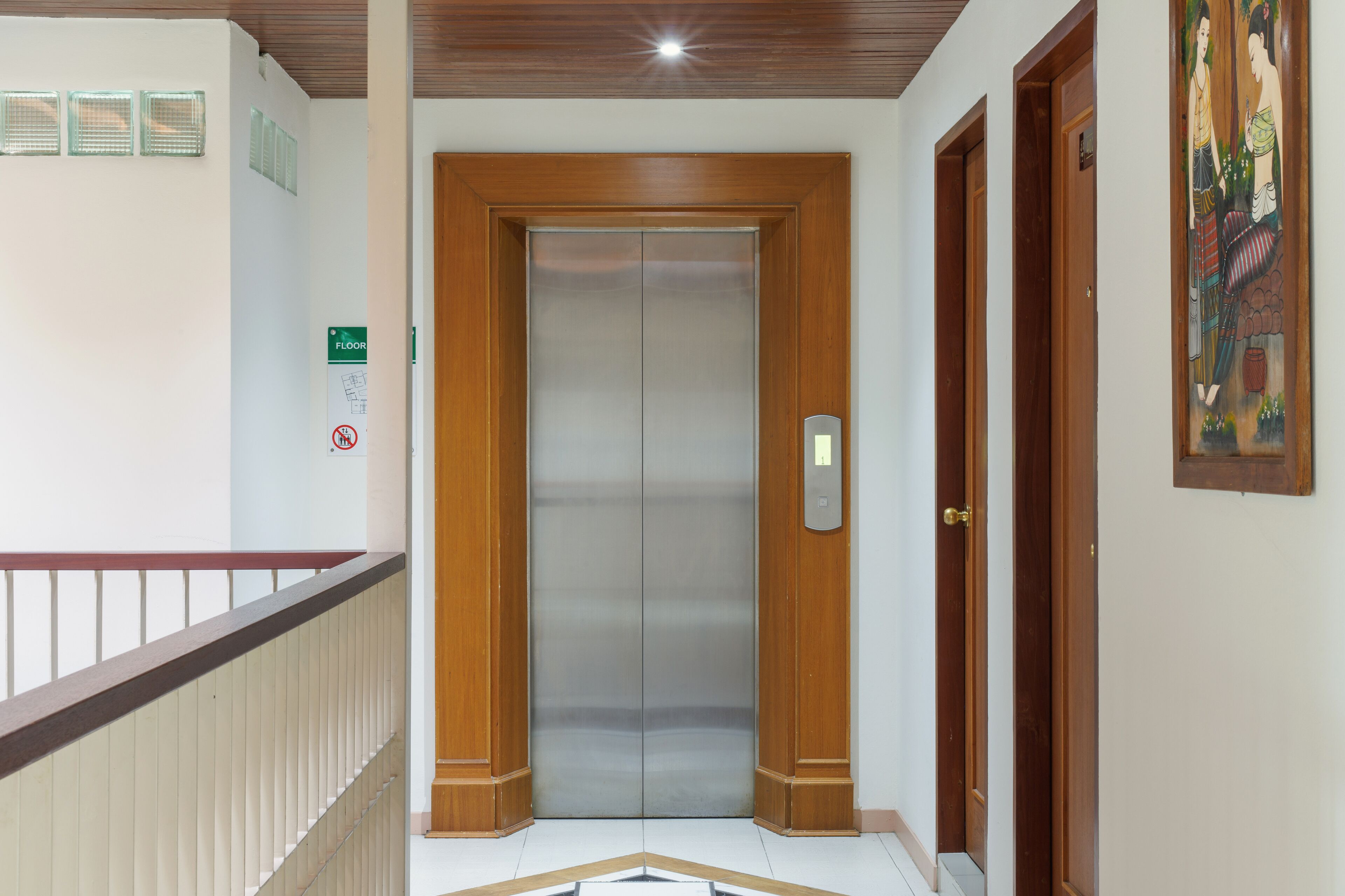 An elevator with wooden doors and a metallic interior, a wooden handrail, and a floor sign indicating the location.
