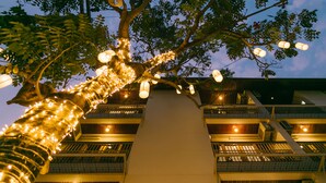 Un edificio con varios balcones, luces de adorno y un árbol iluminado.