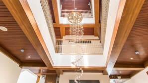 Un interior de varios niveles con vigas de madera, una lámpara colgante en el centro y una escalera.