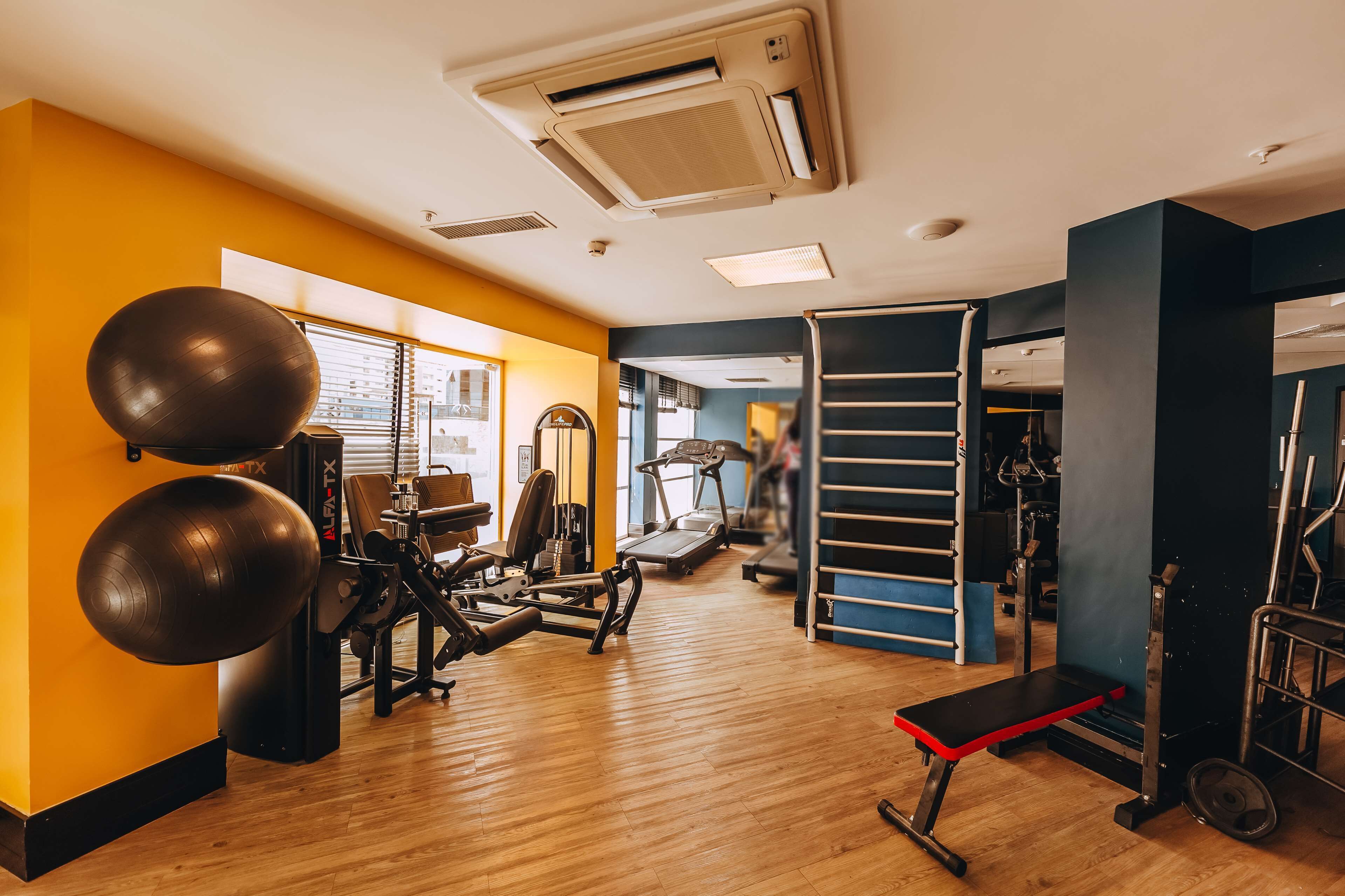 Une salle de sport équipée de matériel d’exercice, d’un tapis de course et d’un banc.