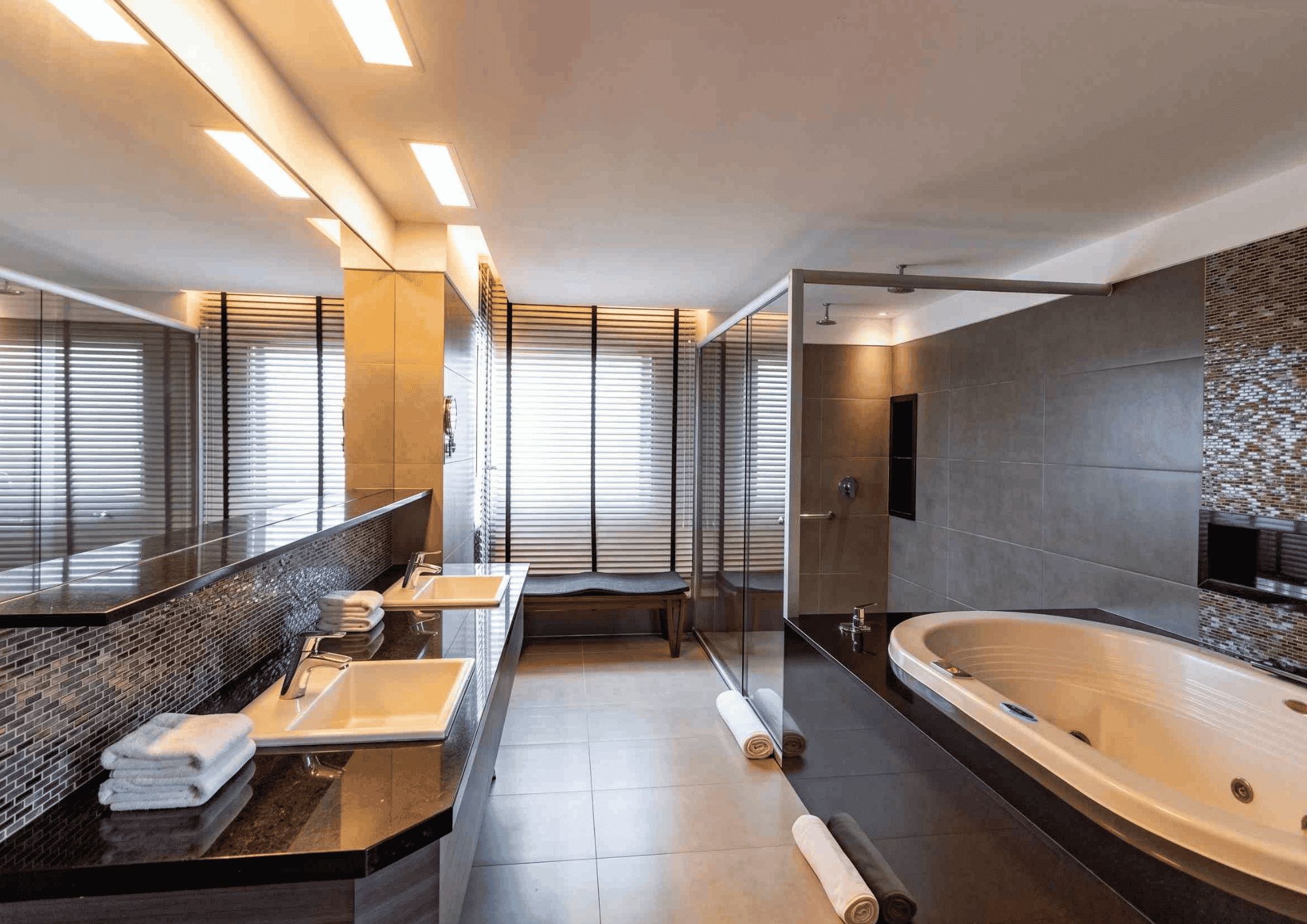 Un baño moderno con una bañera grande, dos lavamanos y un banco.