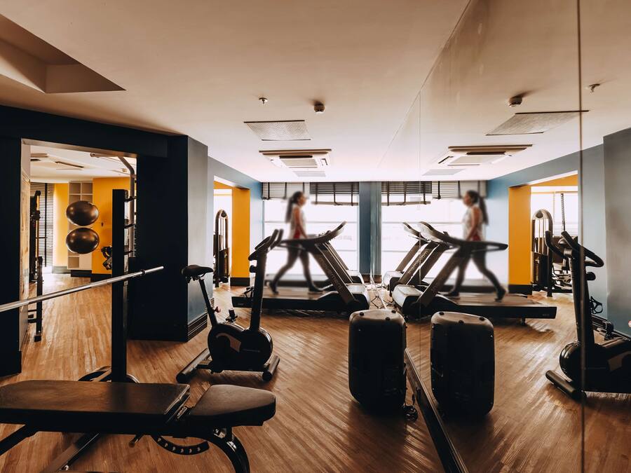 Un gimnasio con cintas de correr, bicicletas estáticas y pesas.