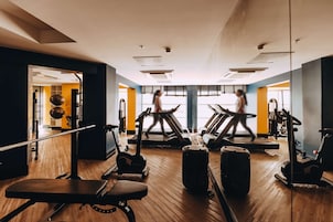 Un gimnasio con cintas de correr, bicicletas estáticas y pesas.