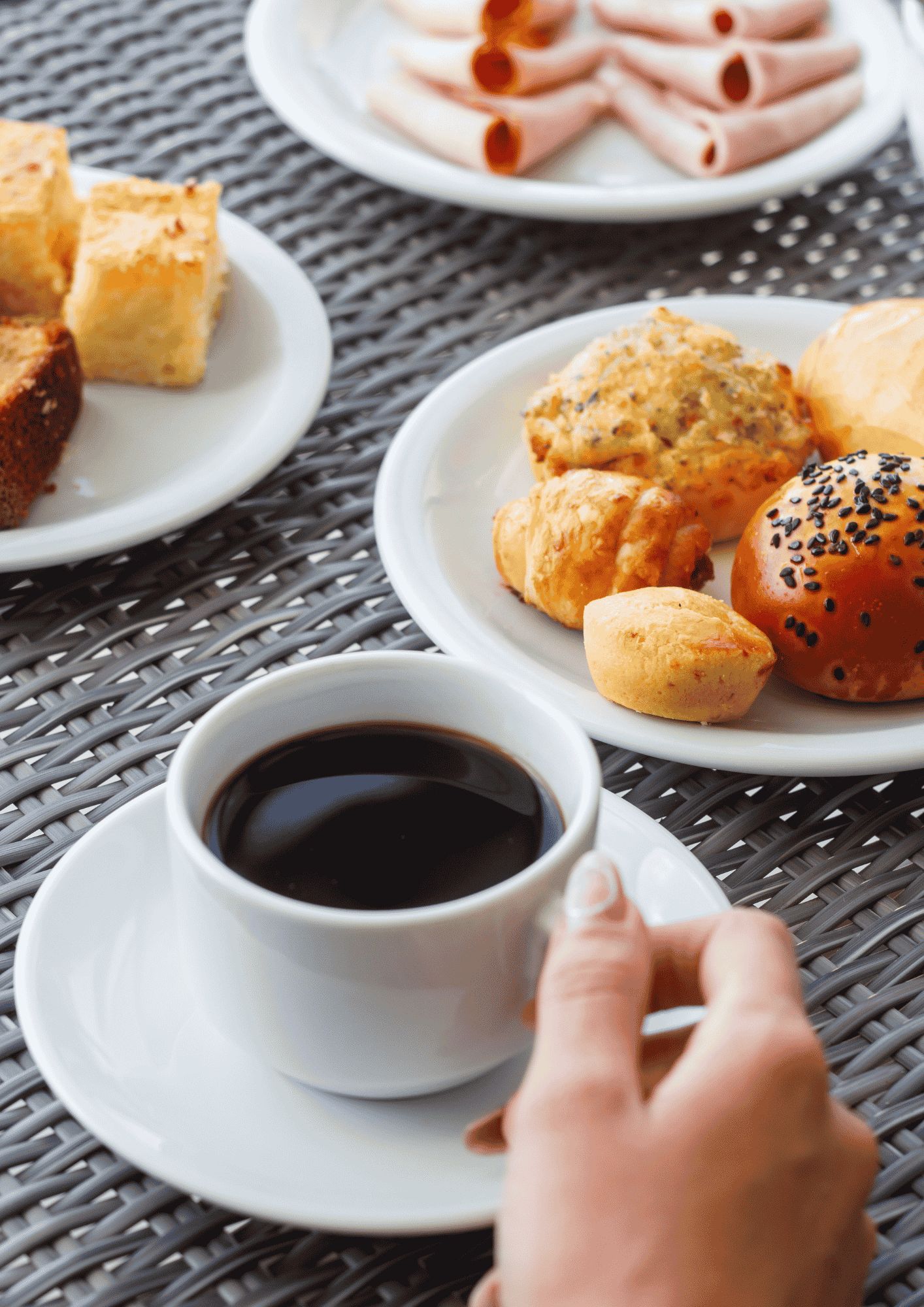 A table with a cup of coffee and various pastries, including croissants and muffins.