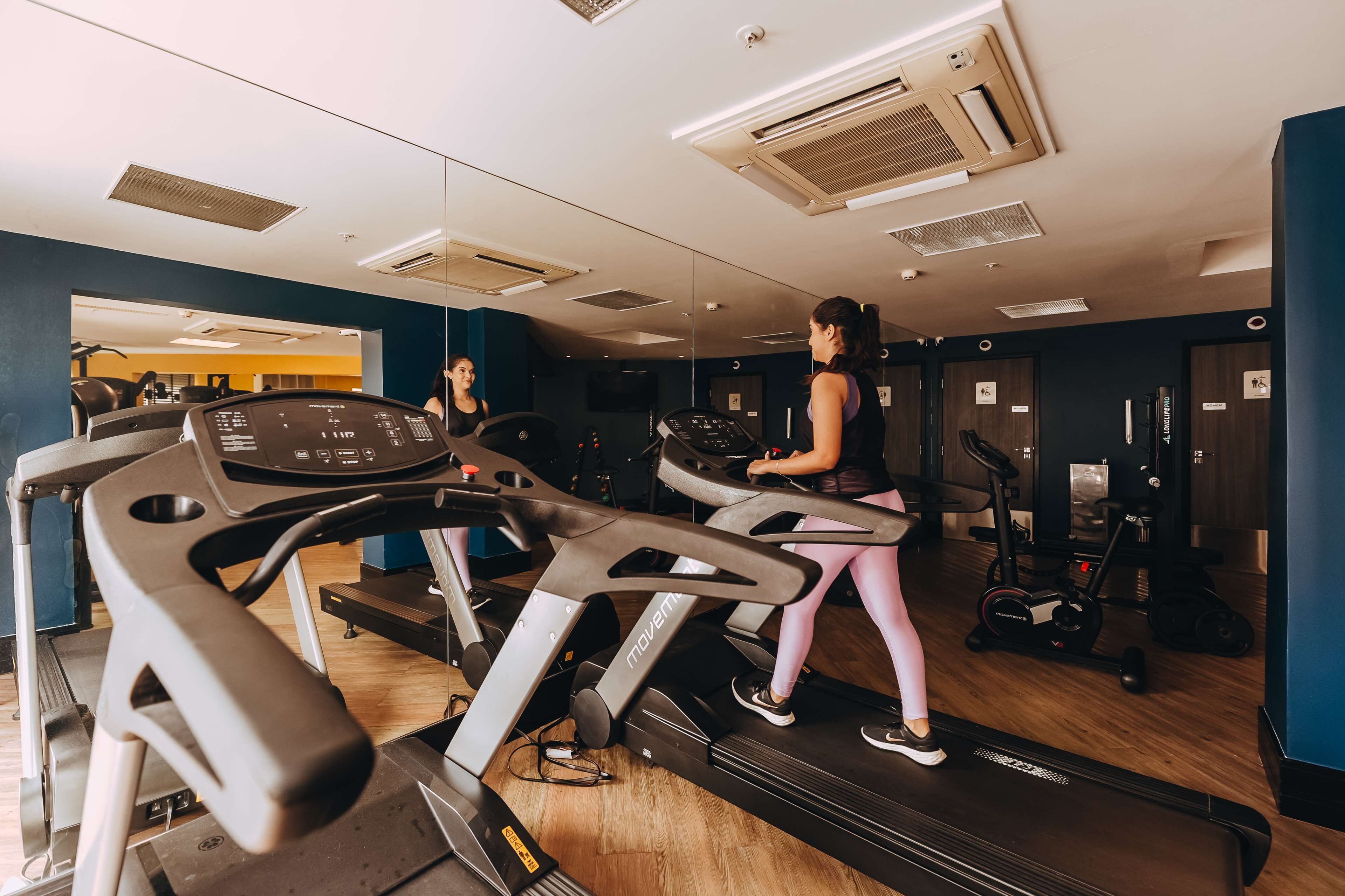 Un gimnasio con cintas de correr, bicicletas estáticas y máquinas de pesas.
