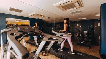 Un gimnasio con cintas de correr, bicicletas estáticas y máquinas de pesas.
