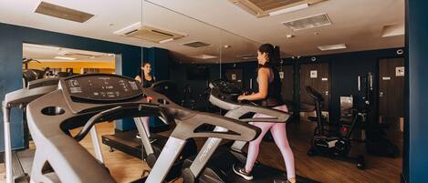A gym with treadmills, exercise bikes, and weight machines.