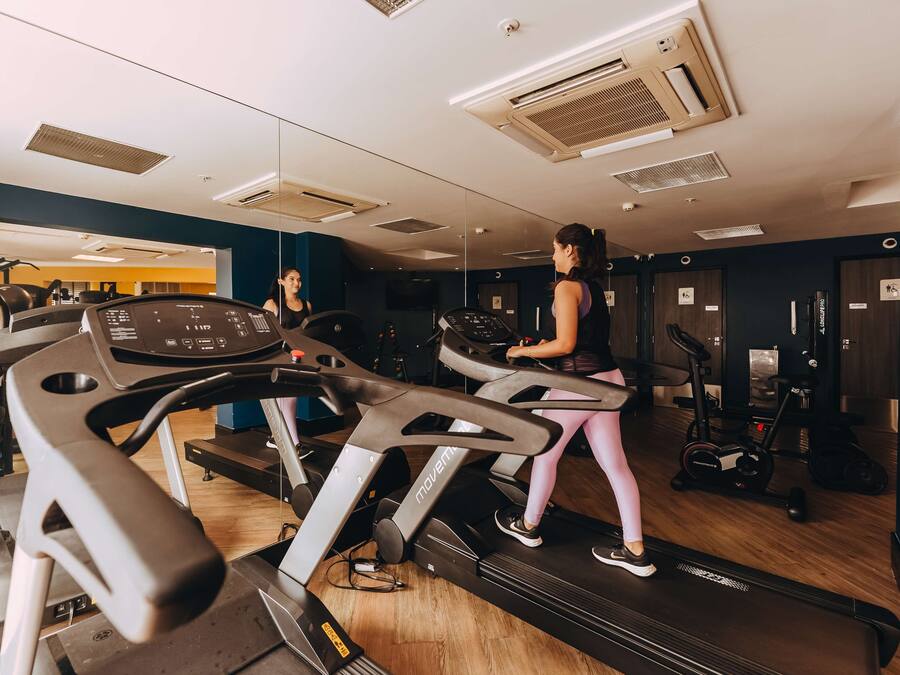 Un gimnasio con cintas de correr, bicicletas estáticas y máquinas de pesas.