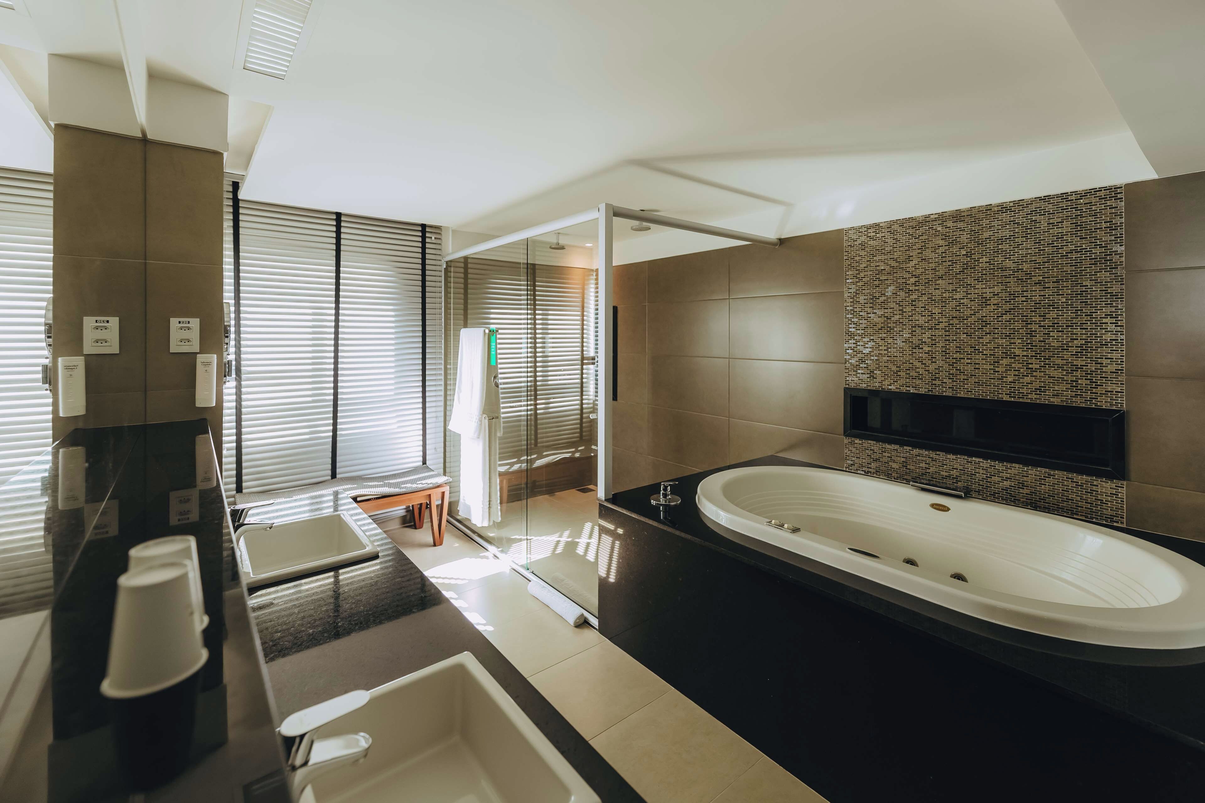 Een moderne badkamer met een groot bad, een aparte douche en een wastafel met spiegel.