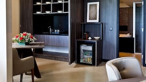 A modern kitchen with a built-in refrigerator, a dining area with chairs, and a small table with a flower arrangement. - Golden Tulip Natal Ponta Negra (Natal)