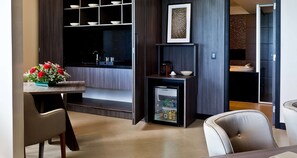 A modern kitchen with a built-in refrigerator, a dining area with chairs, and a small table with a flower arrangement. - Golden Tulip Natal Ponta Negra (Natal)