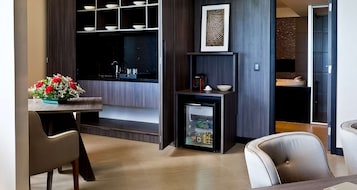 Una cocina moderna con refrigerador empotrado, un comedor con sillas y una mesa pequeña con un arreglo floral.