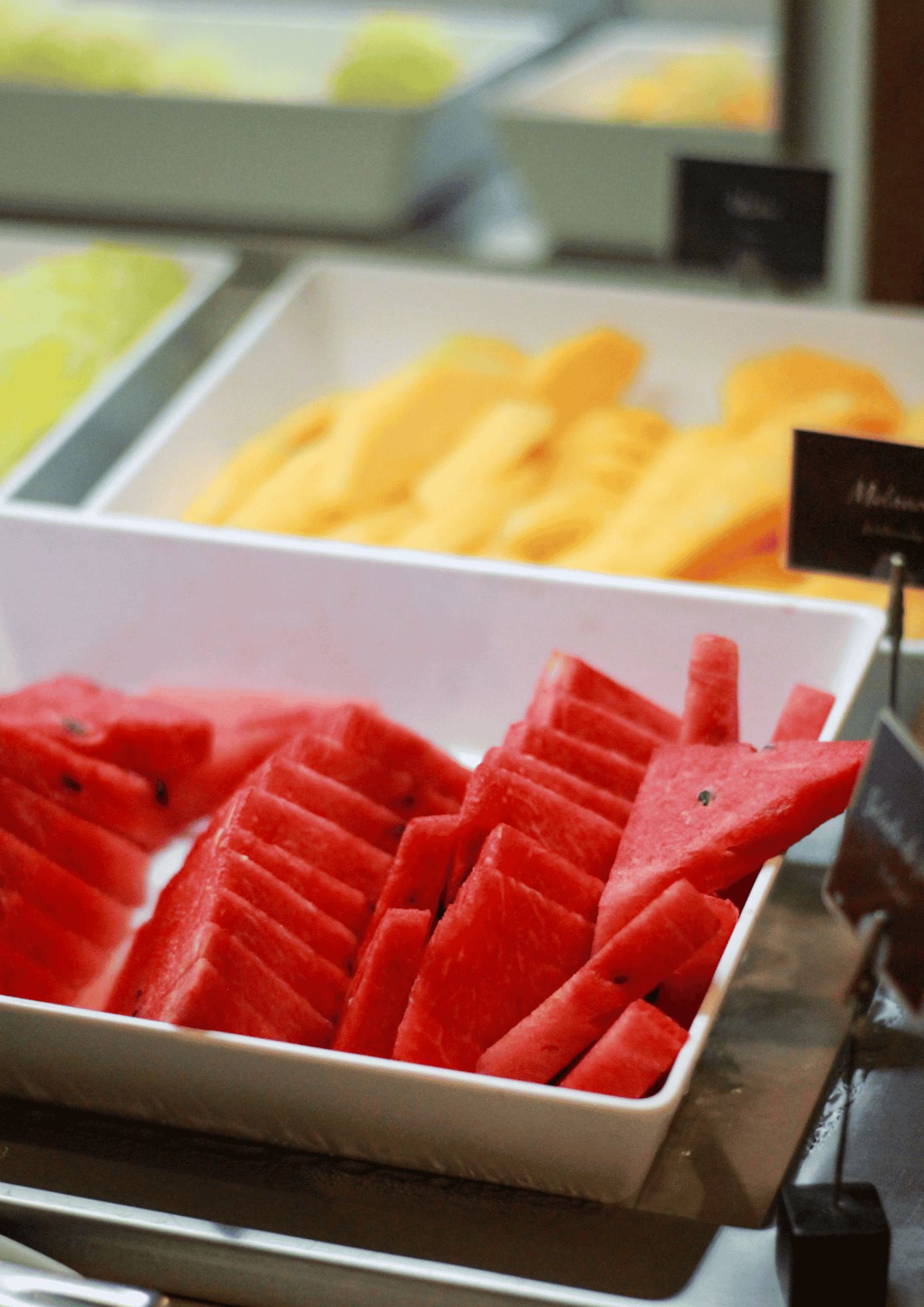 Exposição de frutas fatiadas em uma seção refrigerada de uma loja.