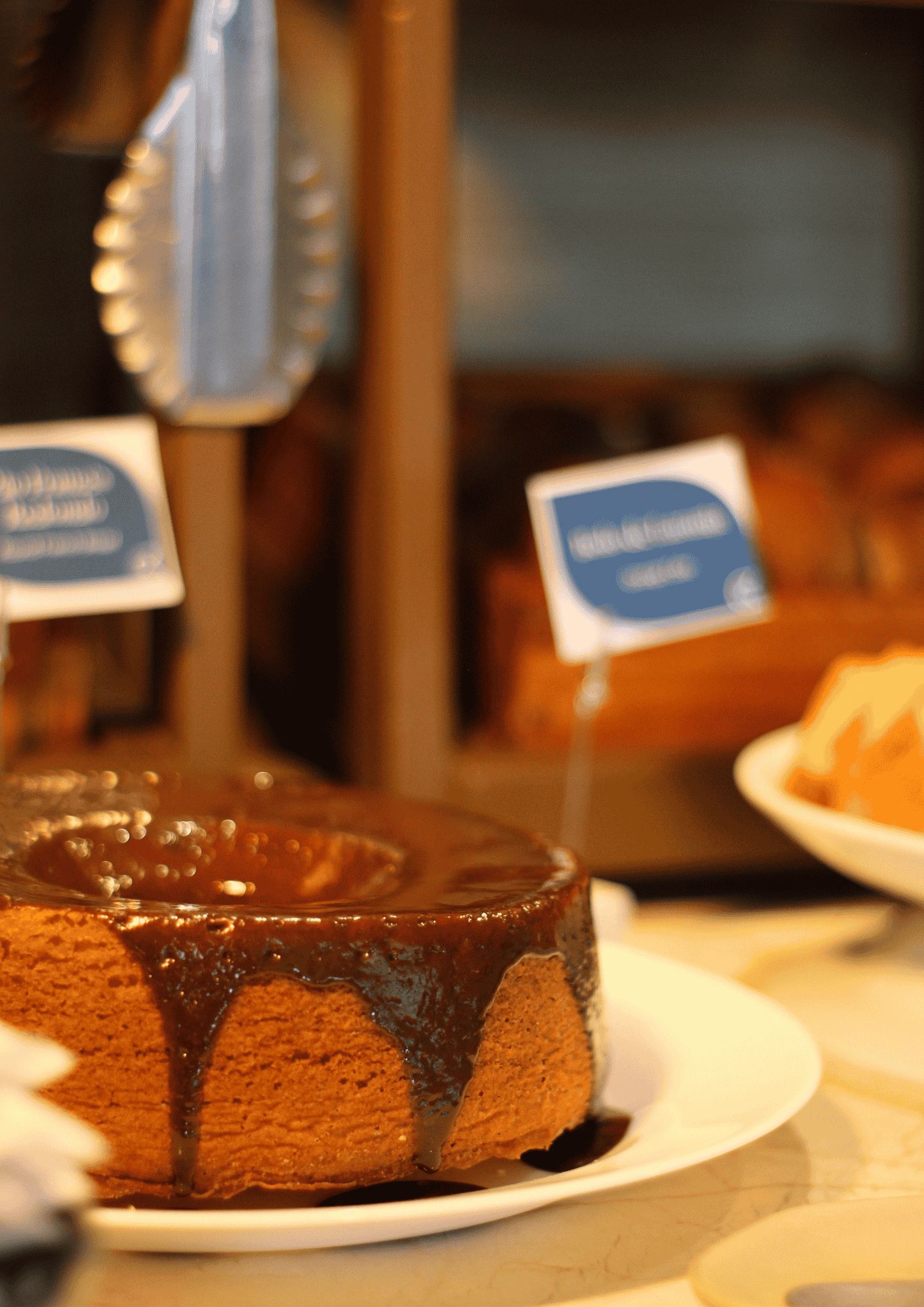 A cake with a glossy chocolate glaze on a white plate.
