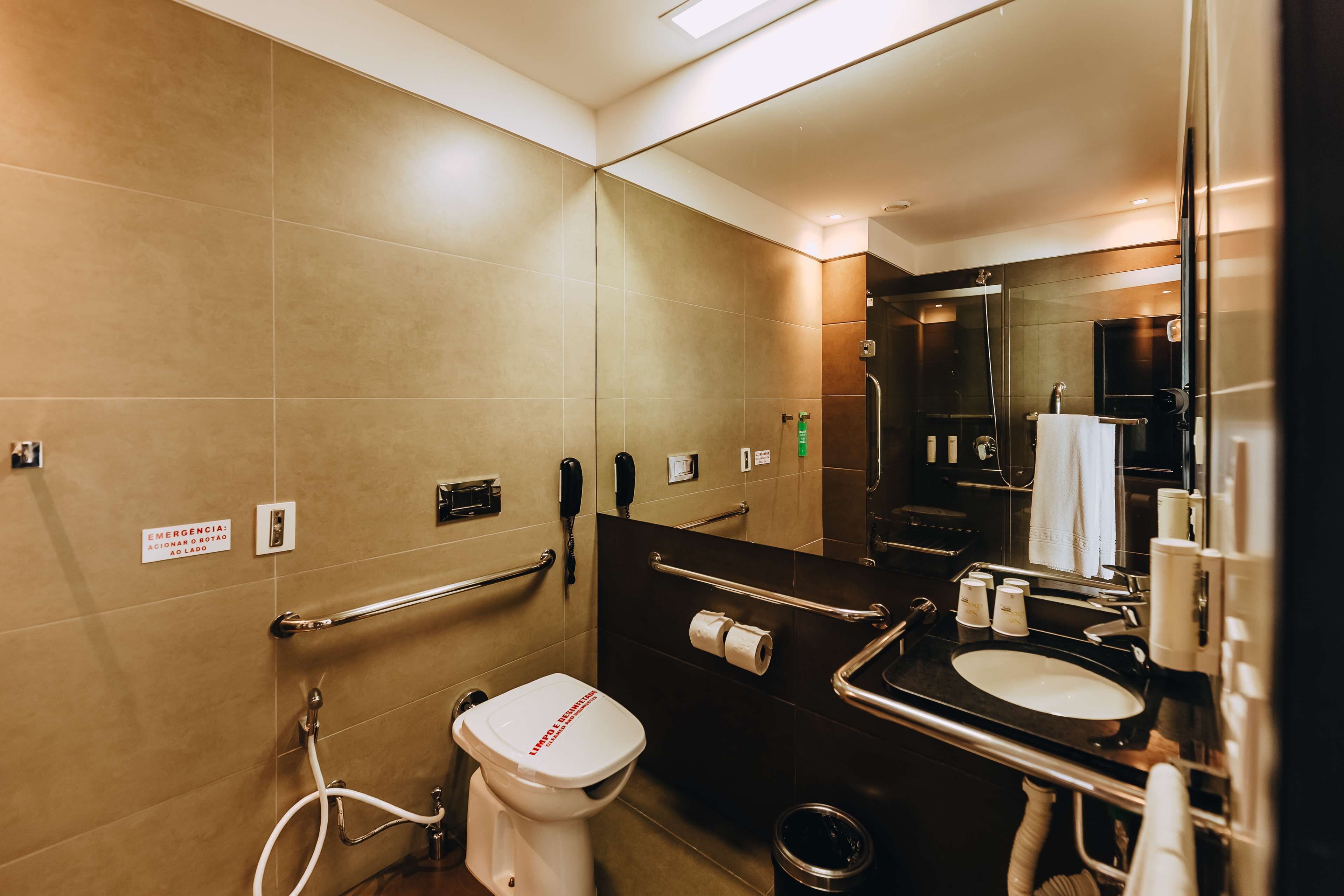 Une salle de bain moderne équipée de toilettes, d’un lavabo et de barres d’appui.