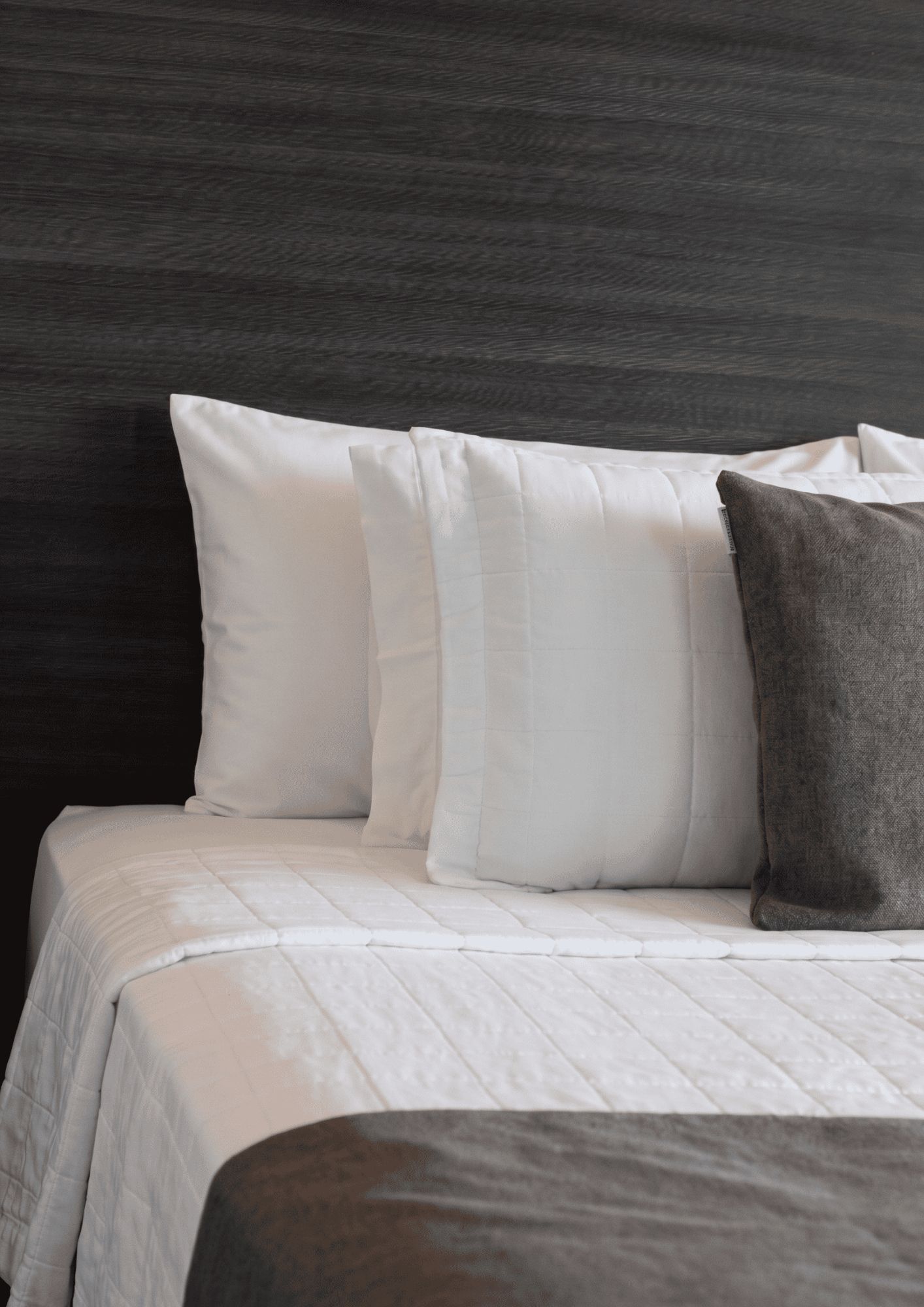 Una cama con ropa de cama blanca y un cabecero oscuro.