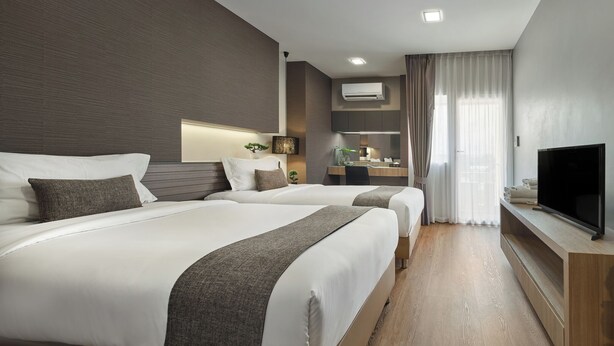 A modern hotel room with two beds, a TV, a desk, and a large window with curtains. - Nap in Fest (Chiang Mai)