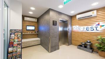 Een modern ingerichte receptiebalie met een receptie, een digitaal scherm en een wandairconditioner.