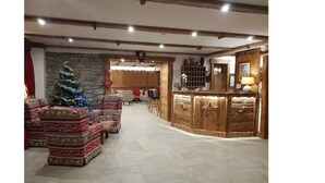 A cozy interior with a Christmas tree, wooden furniture, and a stone wall. - Hotel Edelweiss (Courmayeur)