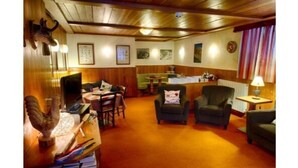 A room with wooden paneling, a dining area with a table and chairs, a sofa, and a lamp. - Hotel Edelweiss (Courmayeur)