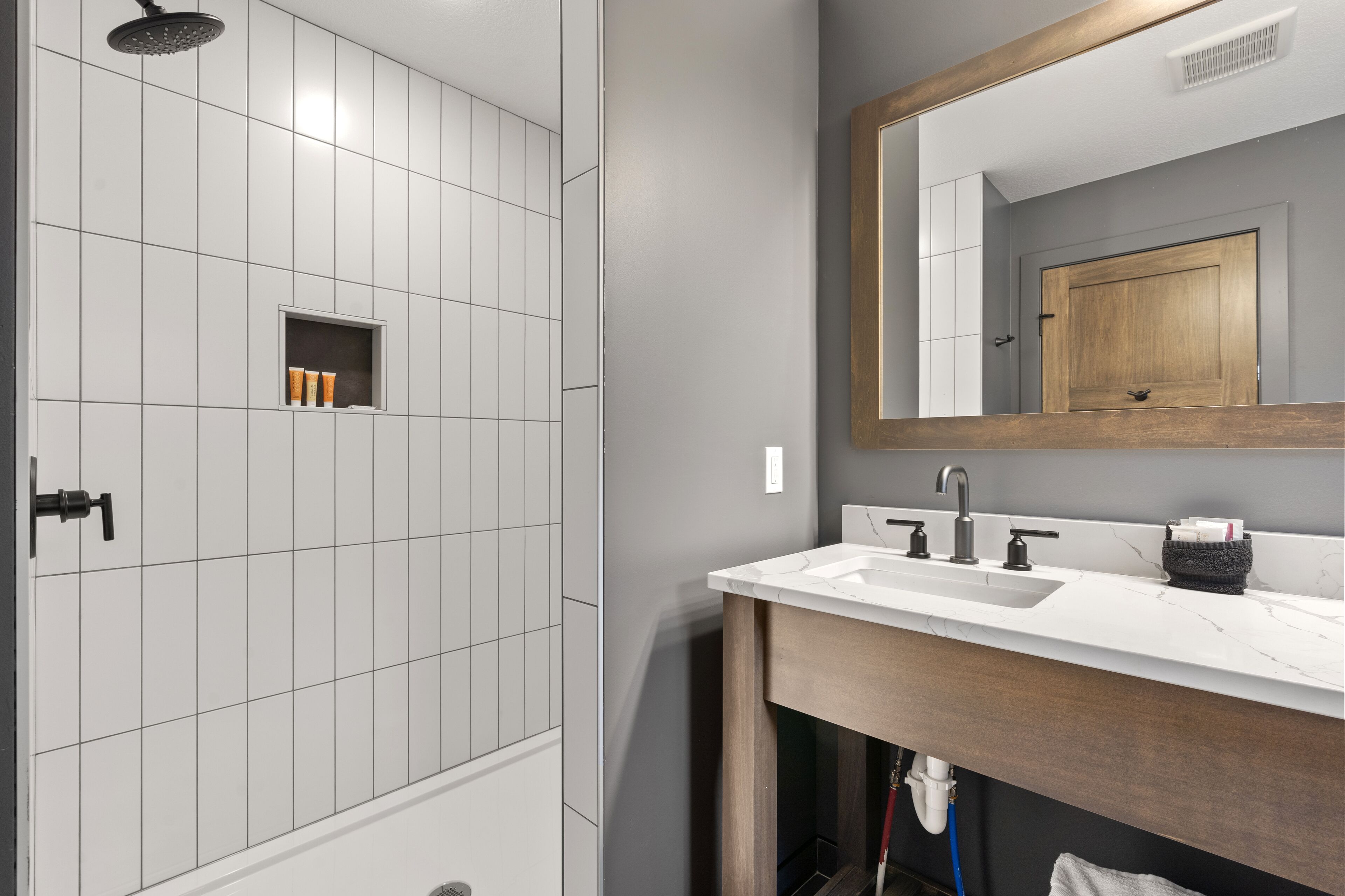 A bathroom with a shower, a sink, and a mirror.