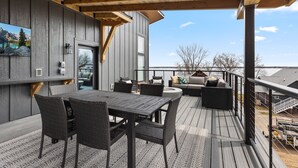 Une terrasse extérieure couverte, équipée d’une table et de chaises, d’un canapé et d’une rambarde.