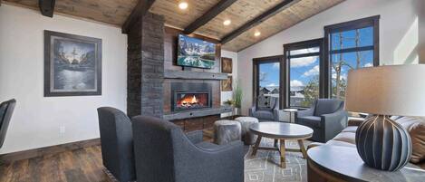 Una sala de estar acogedora con chimenea, asientos cómodos y ventanas amplias que ofrecen una vista.