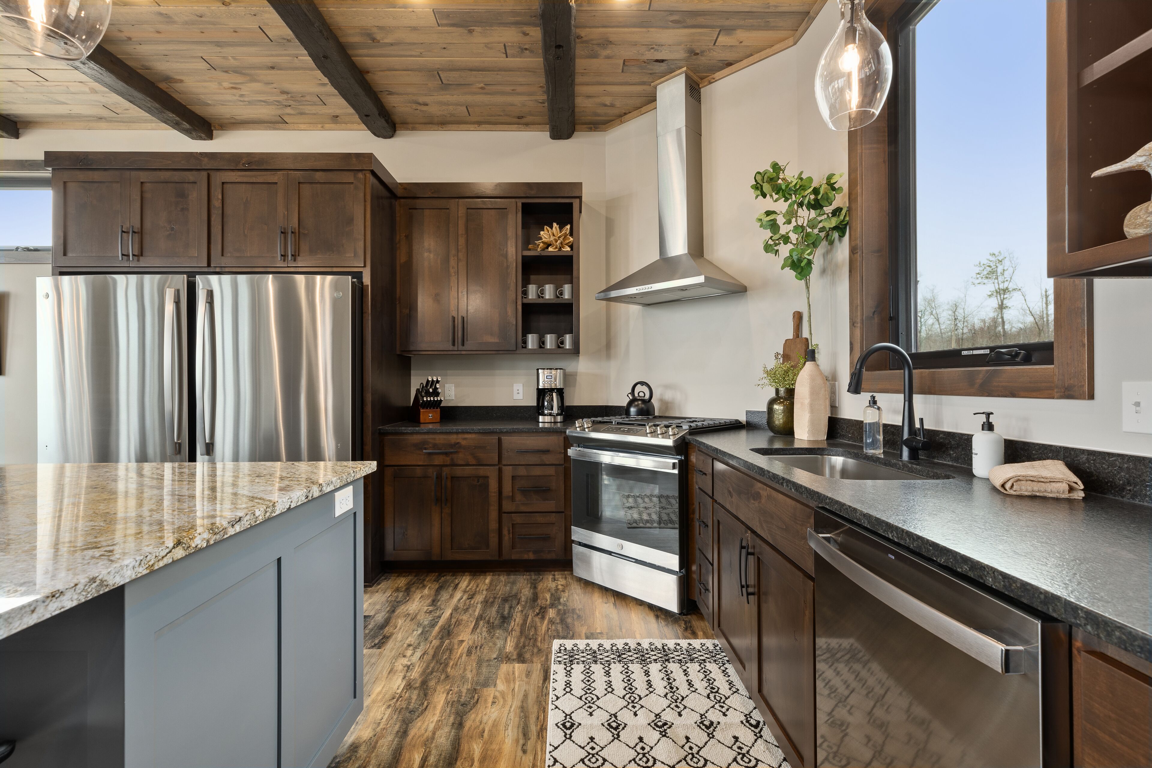 Une cuisine moderne dotée d’appareils électroménagers en acier inoxydable, de meubles en bois et d’une grande fenêtre.
