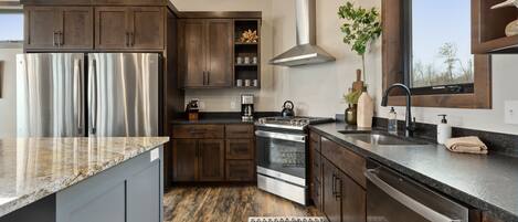 Una cocina moderna con electrodomésticos de acero inoxidable, armarios de madera y un ventanal amplio.