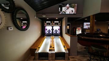 Enjoy a game of bowling at this indoor bowling alley featuring two lanes, a bar area, and a large mirror.
