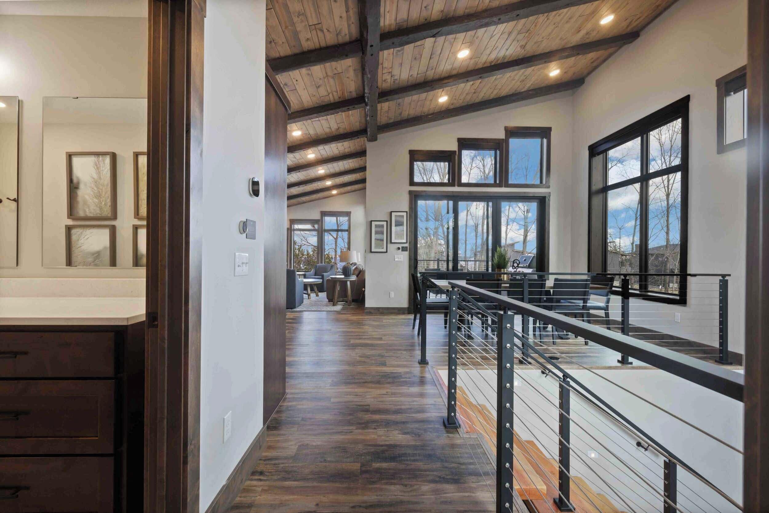A spacious interior with a high ceiling, wooden beams, and large windows offering views of the outdoors.