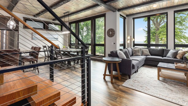 Un vaste espace de vie comprenant un grand canapé d’angle, une table à manger et un escalier avec une rampe en bois.
