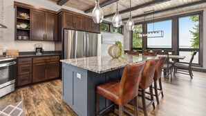 Une cuisine moderne avec des meubles en bois foncé, un réfrigérateur en acier inoxydable et un grand îlot central doté de tabourets de bar.