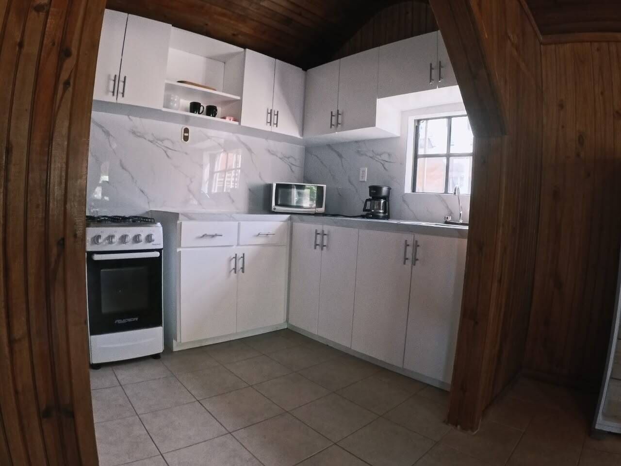 A kitchen with white cabinets, a stove, a microwave, and a coffee maker.