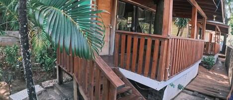Una cabaña de madera con un porche, rodeada de vegetación tropical.