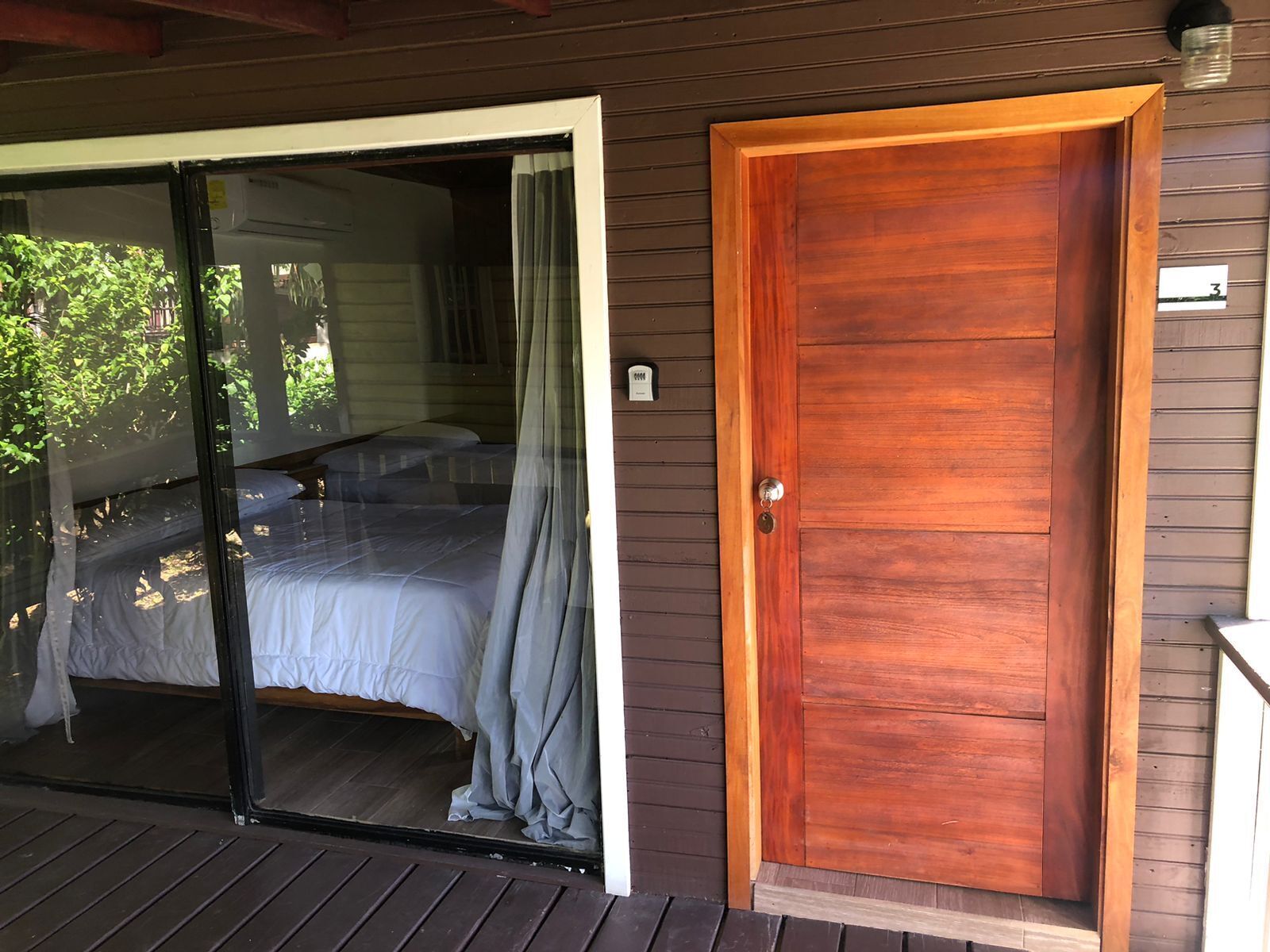 A room with a sliding glass door leading to a balcony, a wooden door, and a small window.
