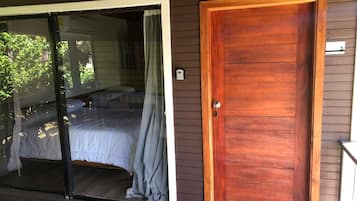 A room with a sliding glass door leading to a balcony, a wooden door, and a small window.