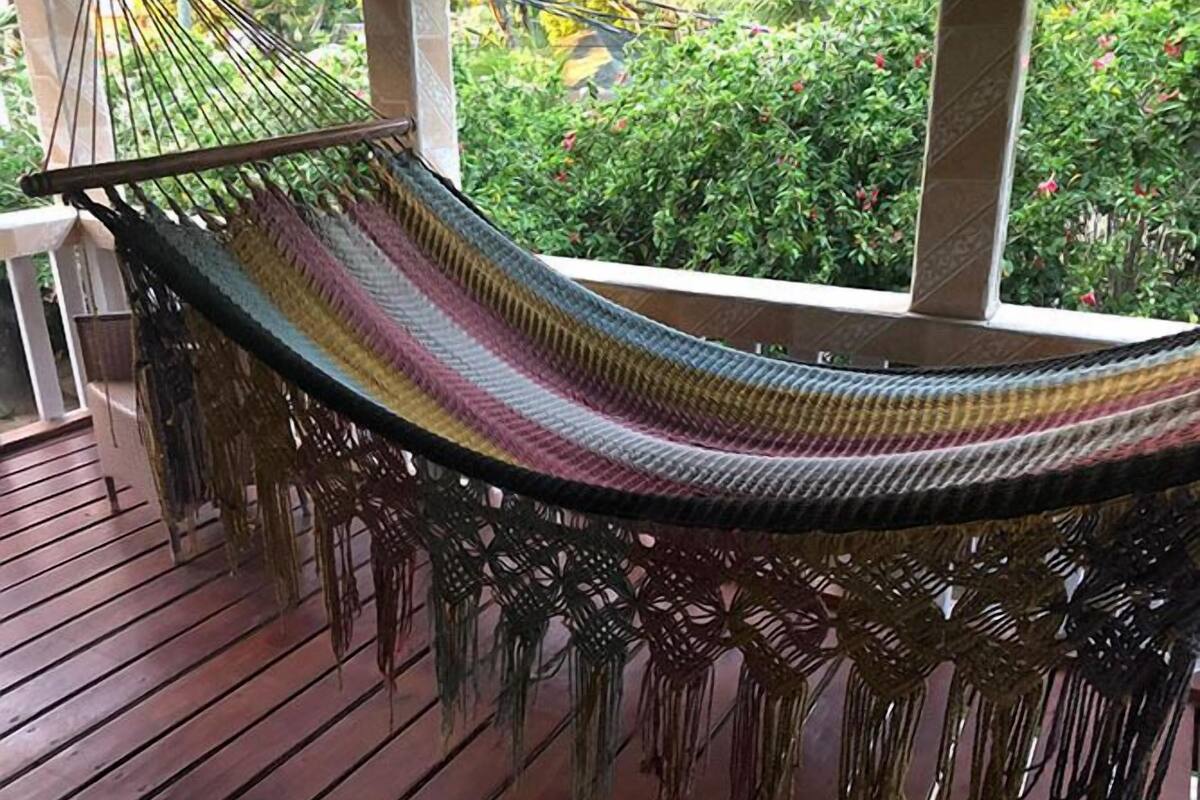 Una hamaca en una terraza de madera con vista a follaje.