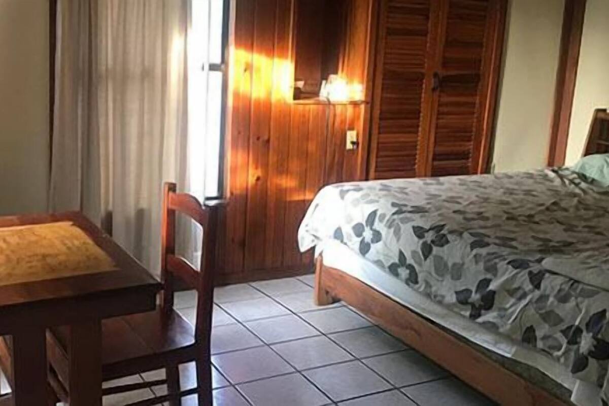Un dormitorio con una cama, una mesa de madera y una silla.