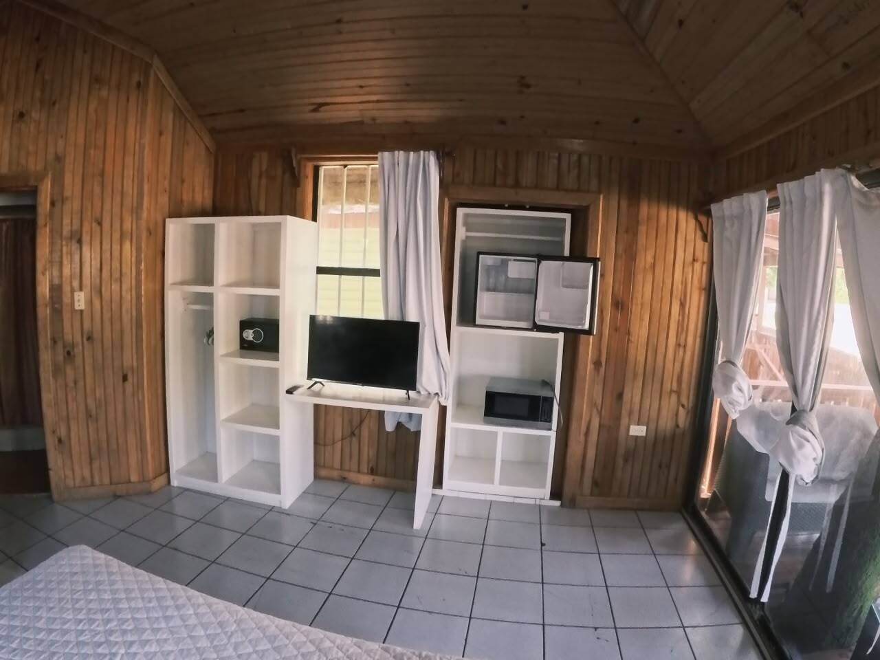 Une pièce équipée d’un téléviseur posé sur un meuble, d’un four à micro-ondes et d’un réfrigérateur.
