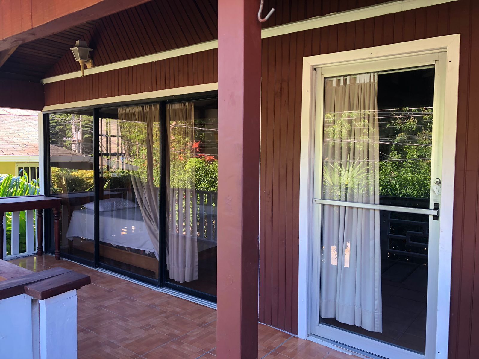 Un espacio al aire libre techado con una puerta corrediza de vidrio y una terraza de madera.