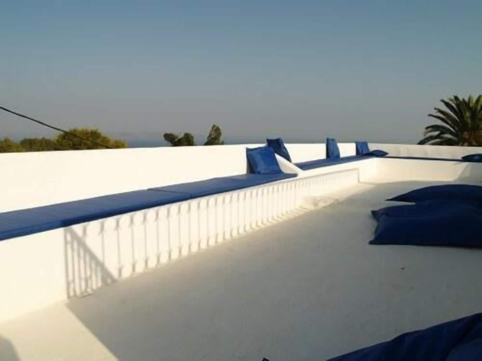 A rooftop terrace with white walls and blue cushions.