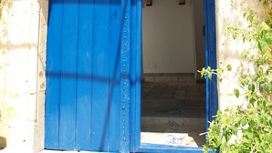 Une porte bleue en arc de cercle, renforcée par des éléments métalliques, qui mène à un bâtiment dont le mur est en pierre.