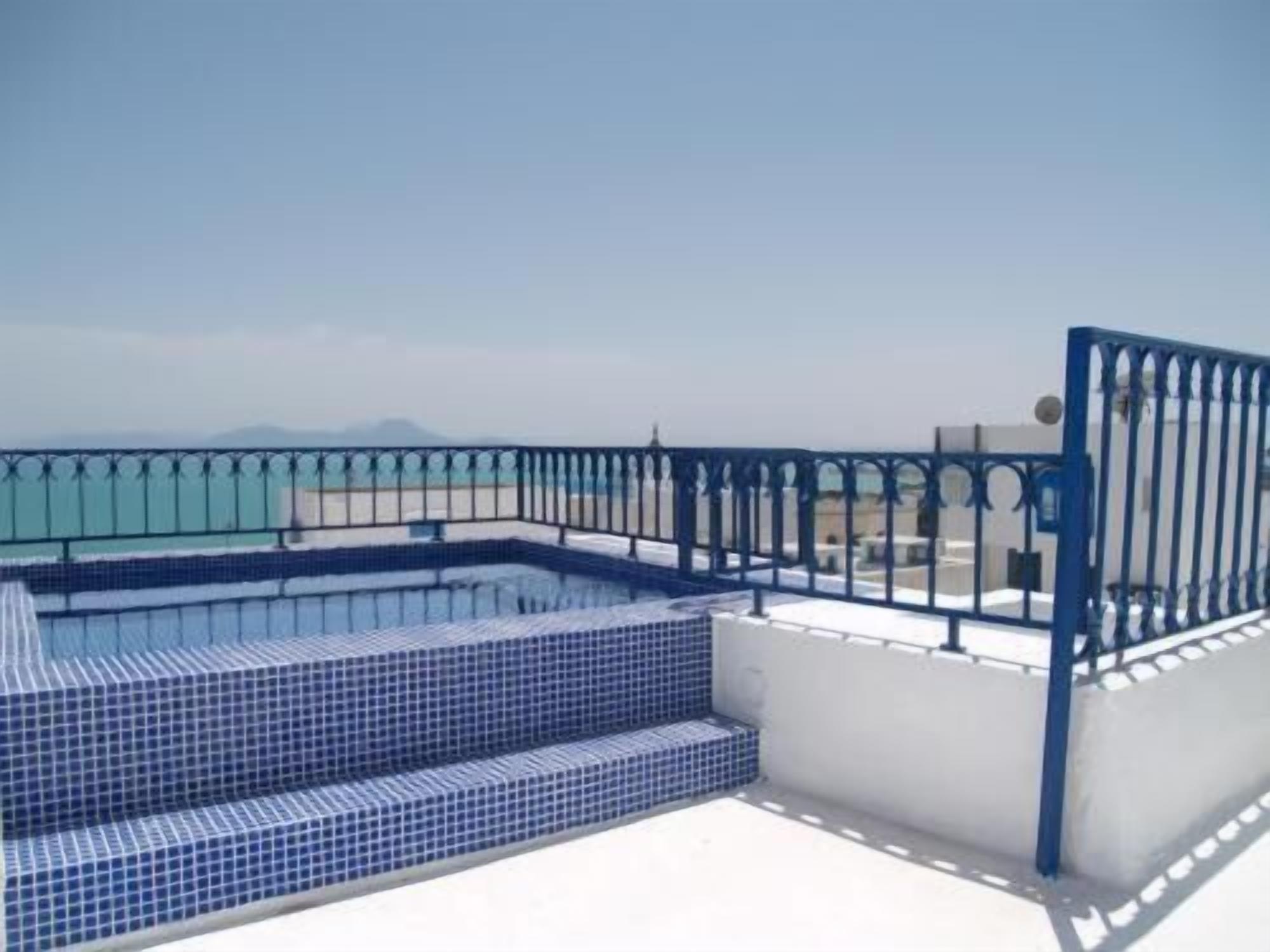 Une piscine sur le toit, avec des marches recouvertes de carreaux bleus et une rambarde en métal bleu.
