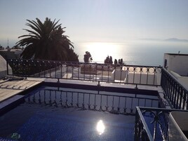 A rooftop pool with a view of the sea and mountains.