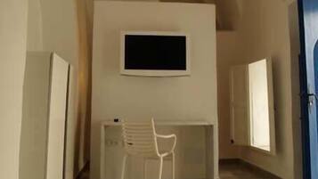 Une pièce comprenant un bureau, une chaise et un téléviseur fixé au mur.